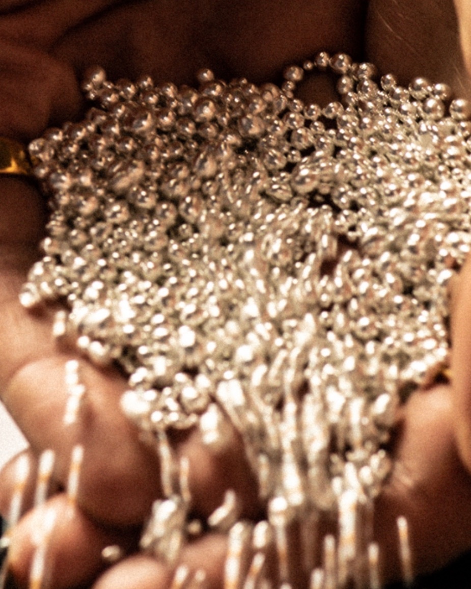 Close up of silver beads pouring from someone's hands onto a table