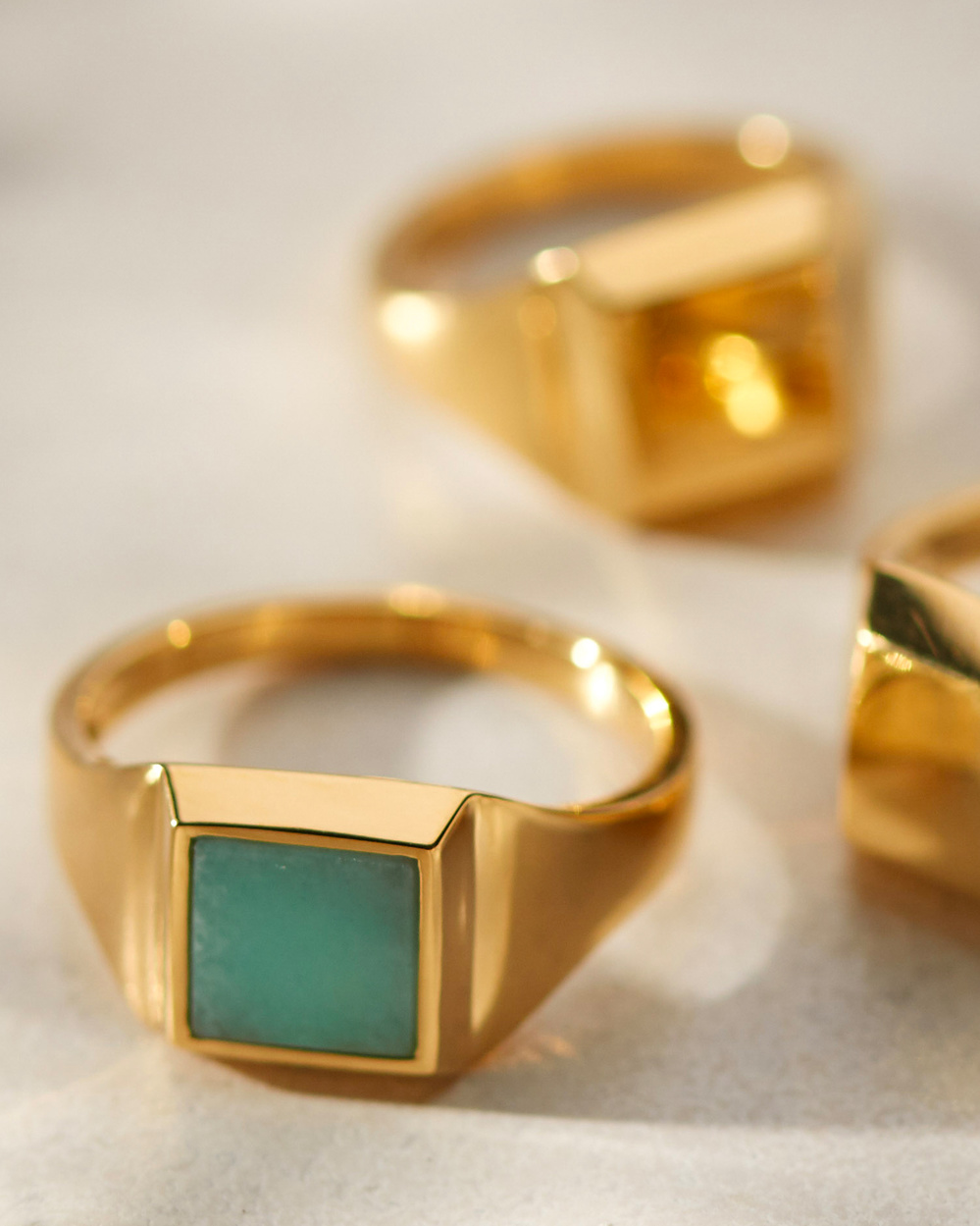 Three gold Monica Vinader Signet Rings, one with Amazonite embedded.