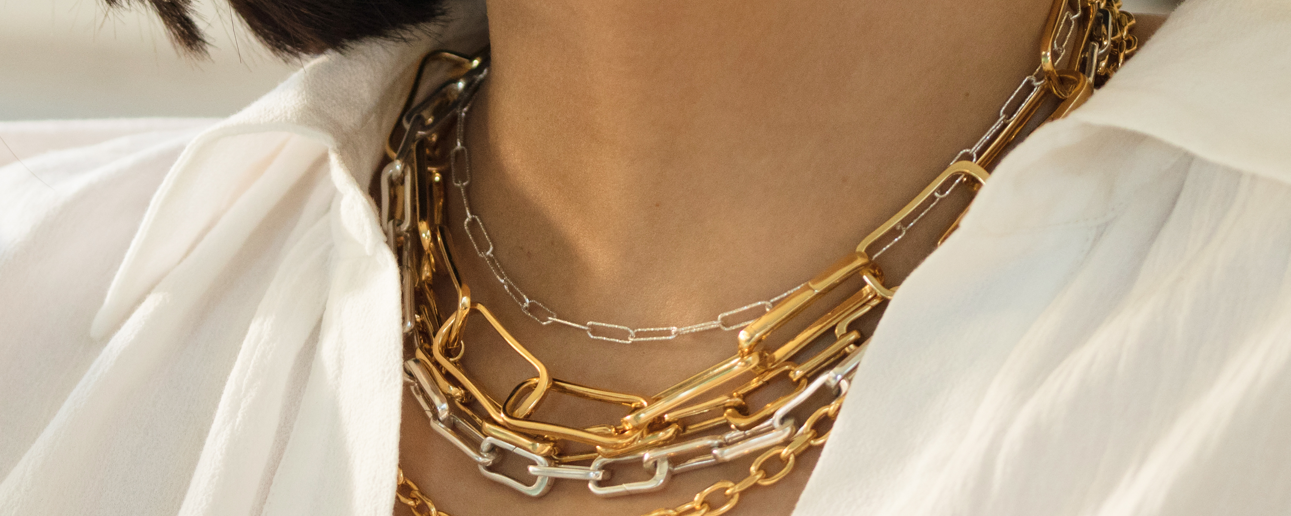 Model wearing a mix of Alta Capture necklaces of different sizes and finishes.