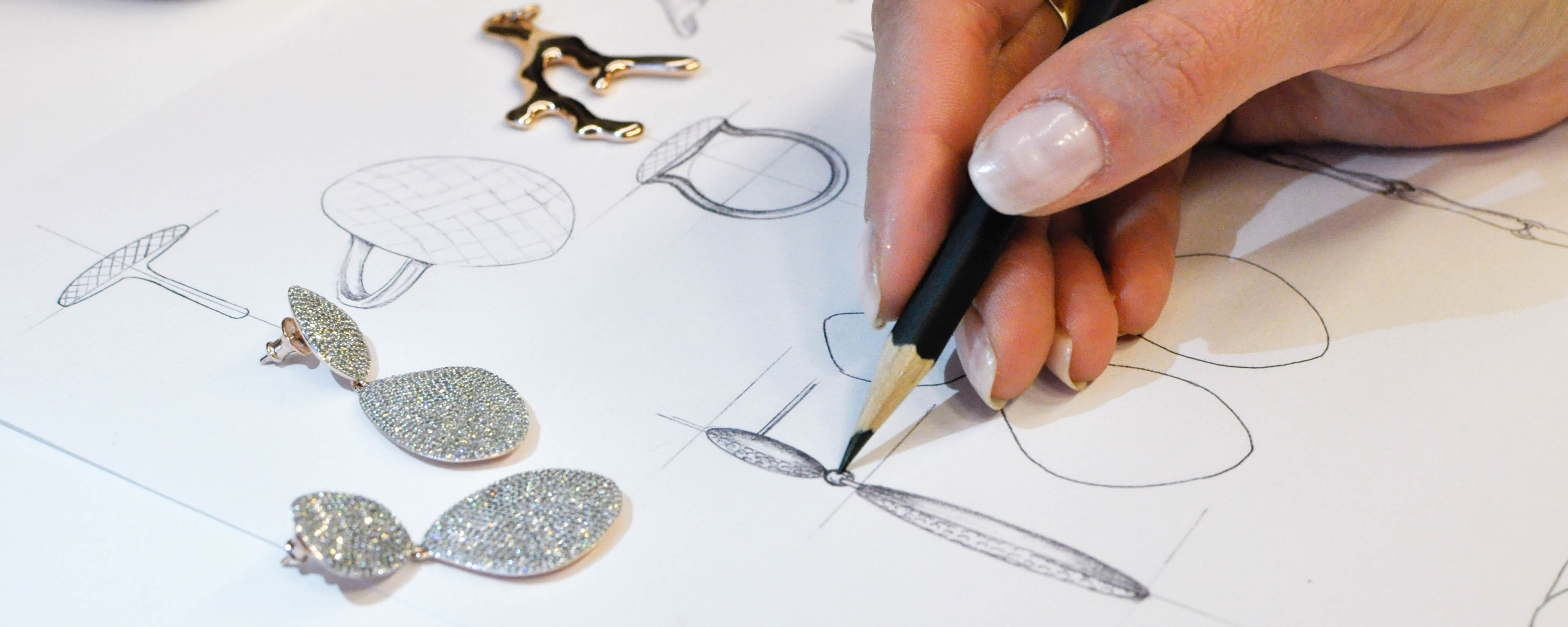 An artist drawing sketches of the Monica Vinader Teardrop Cocktail Earrings