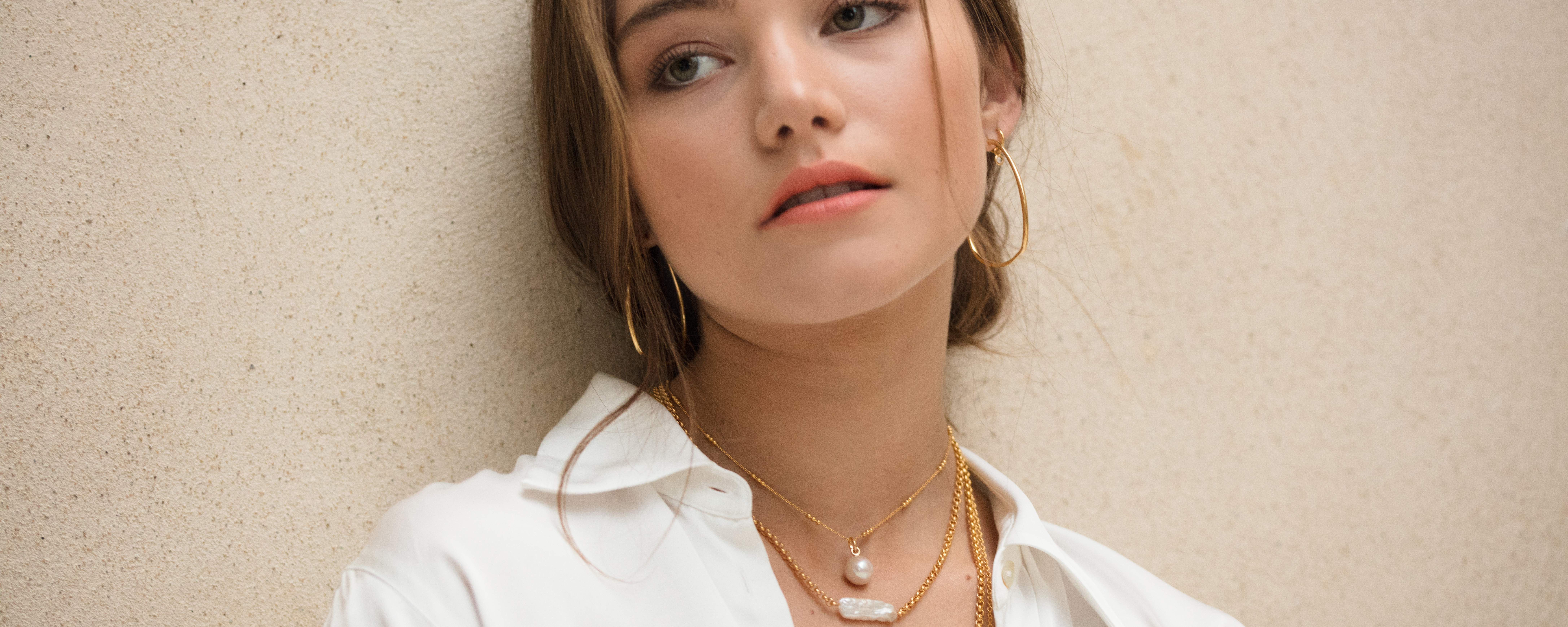 A model styling the Monica Vinader Biwa Pearl Necklace, layered with a Nura Baroque Pearl on gold chains.